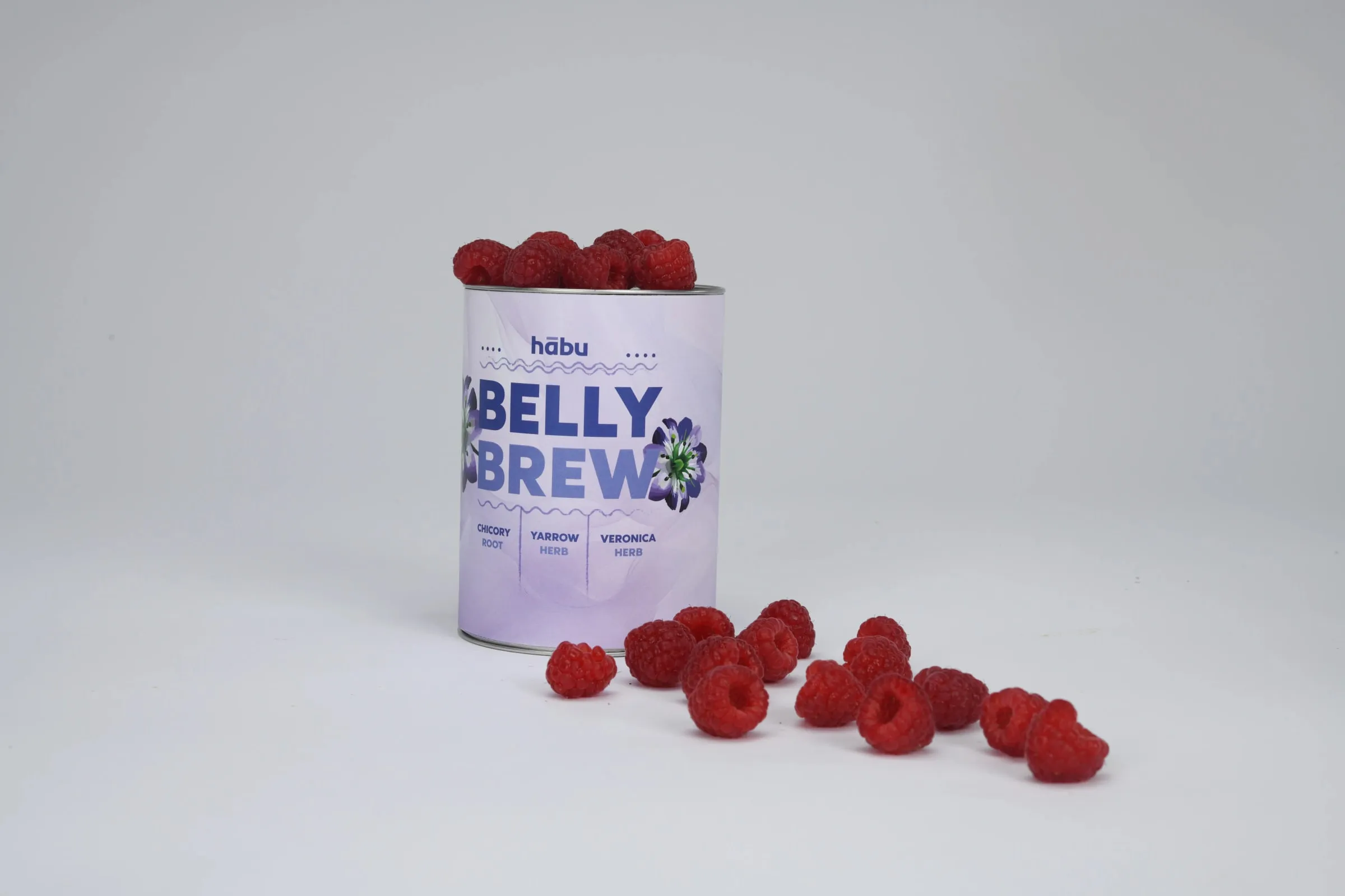 A Belly Brew tin with red berries piled on top and scattered around its base.