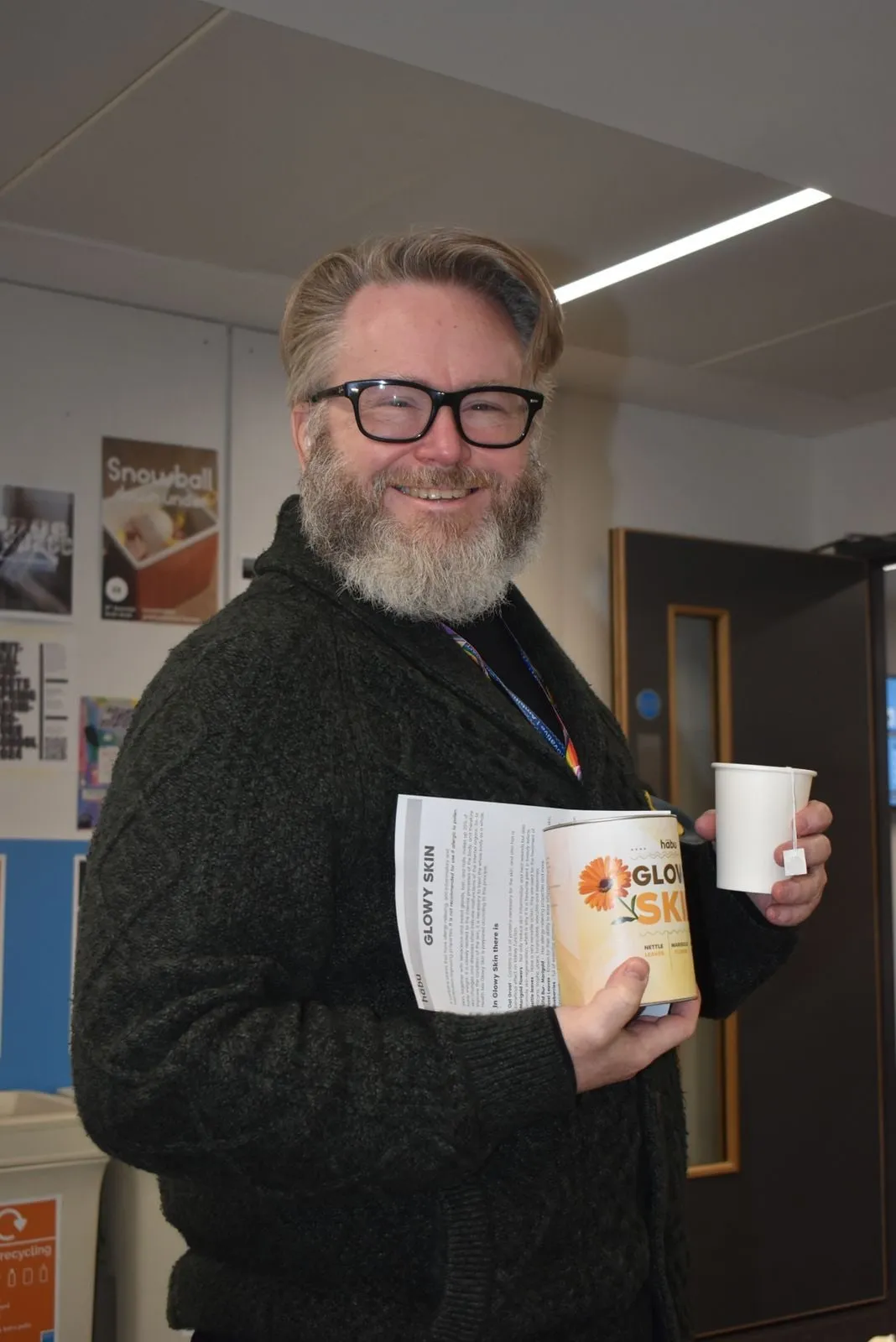 A smiling customer at the launch holding a Habu leaflet and a cup of tea.