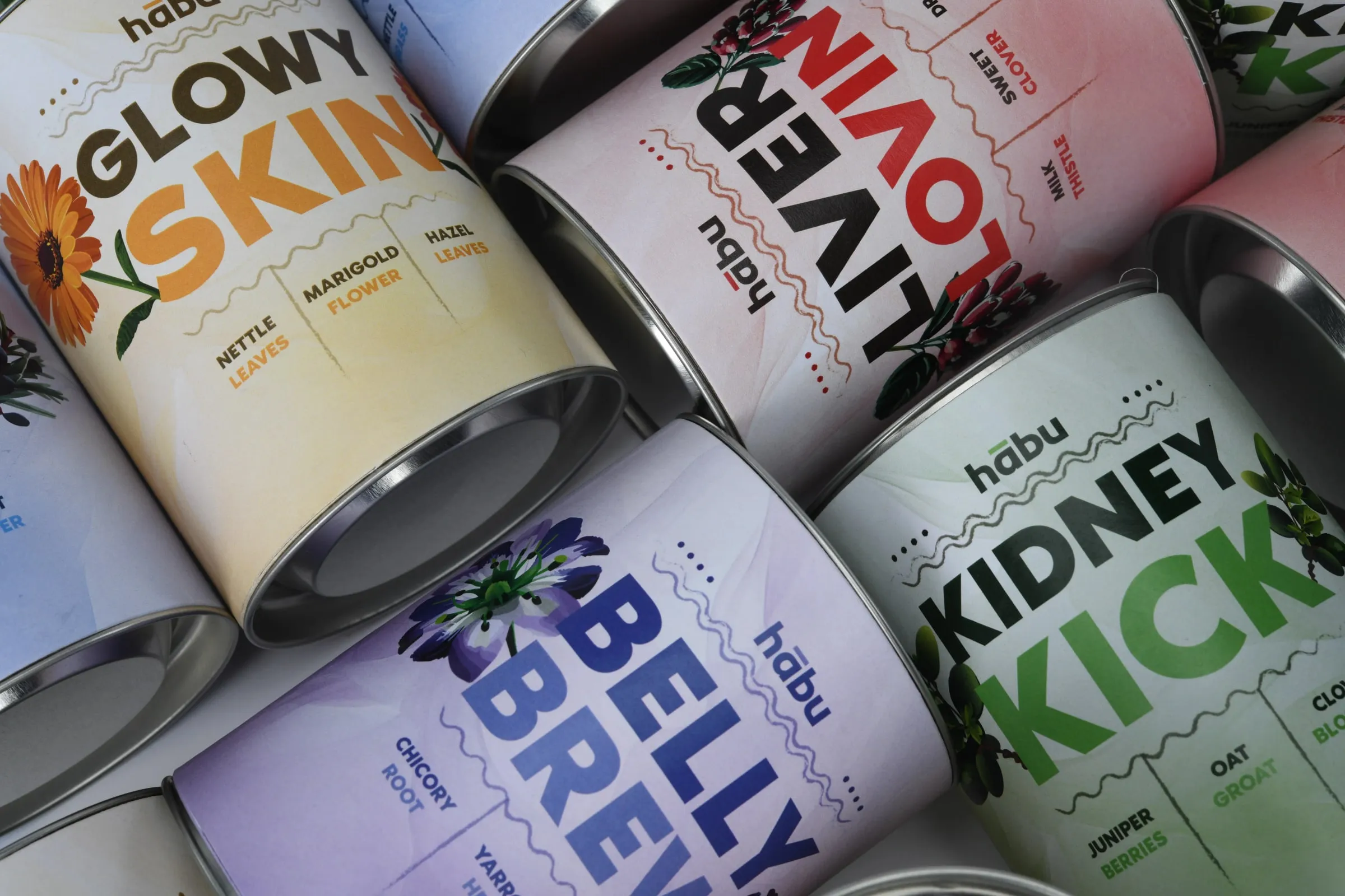 Close-up of Habu tins lying together, the Glowy Skin, Liver Lovin', Belly Brew and Kidney Kick labels side by side.
