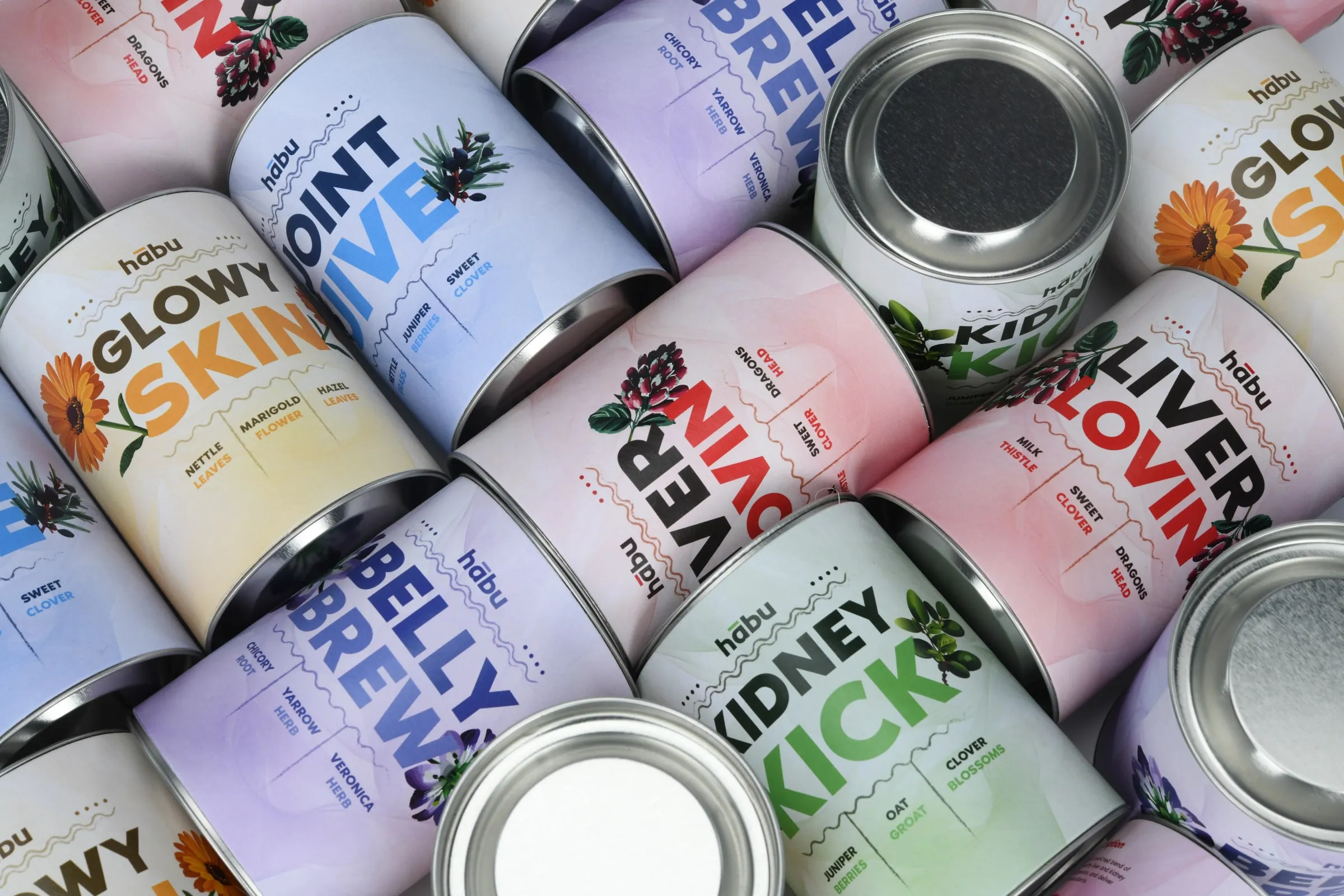 Habu tins in all five colours piled together, some showing their labels and some their open silver ends.